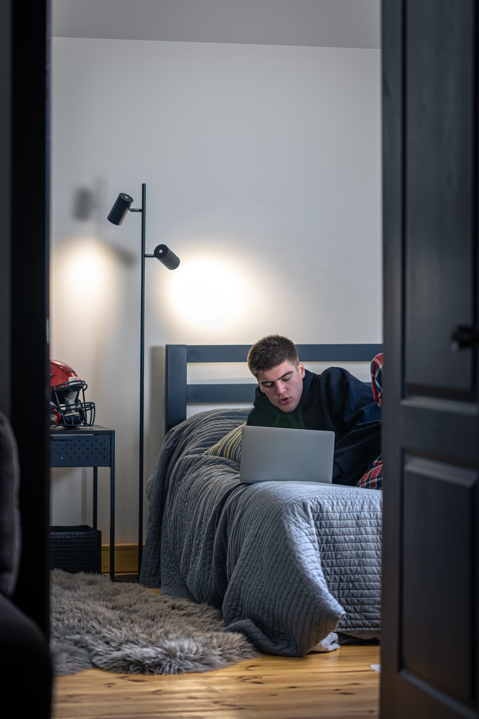 resized_teenager-guy-sits-room-bed-uses-laptop