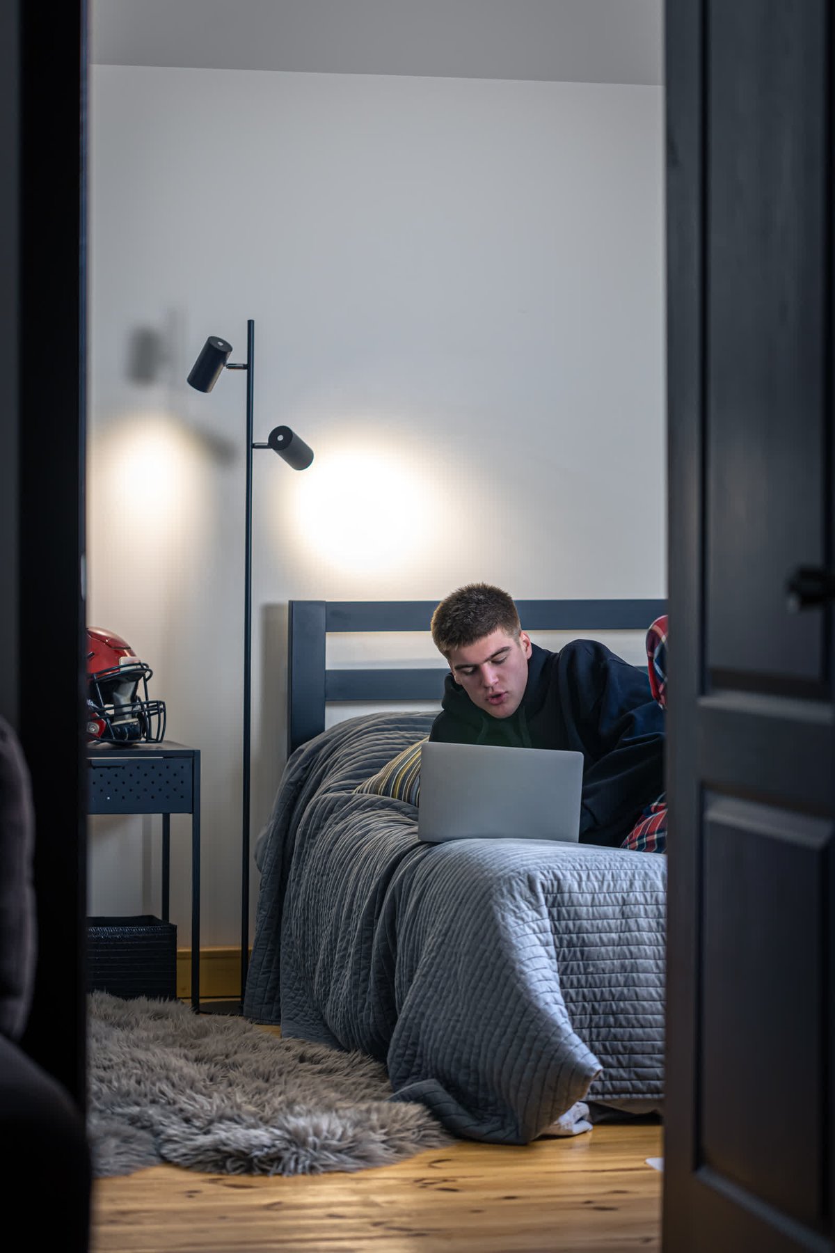 resized_teenager-guy-sits-room-bed-uses-laptop