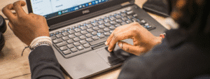 A person's hands typing on a laptop computer, representing someone researching important financial decisions such as understanding the risks of being a guarantor for rent before making commitments that could impact their financial security.
